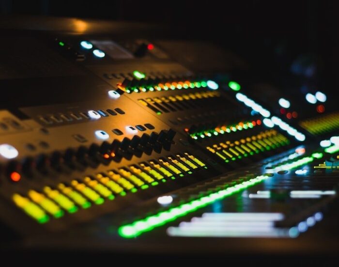 Ljudmixer med upplysta equalizerskjutreglage i mörk studio