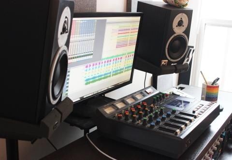 Hemmastudio med monitorhögtalare, mixerbord och ljudprogram på skärm