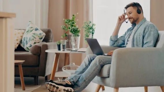 Man arbetar hemma med bärbara datorn och hörlurar på
